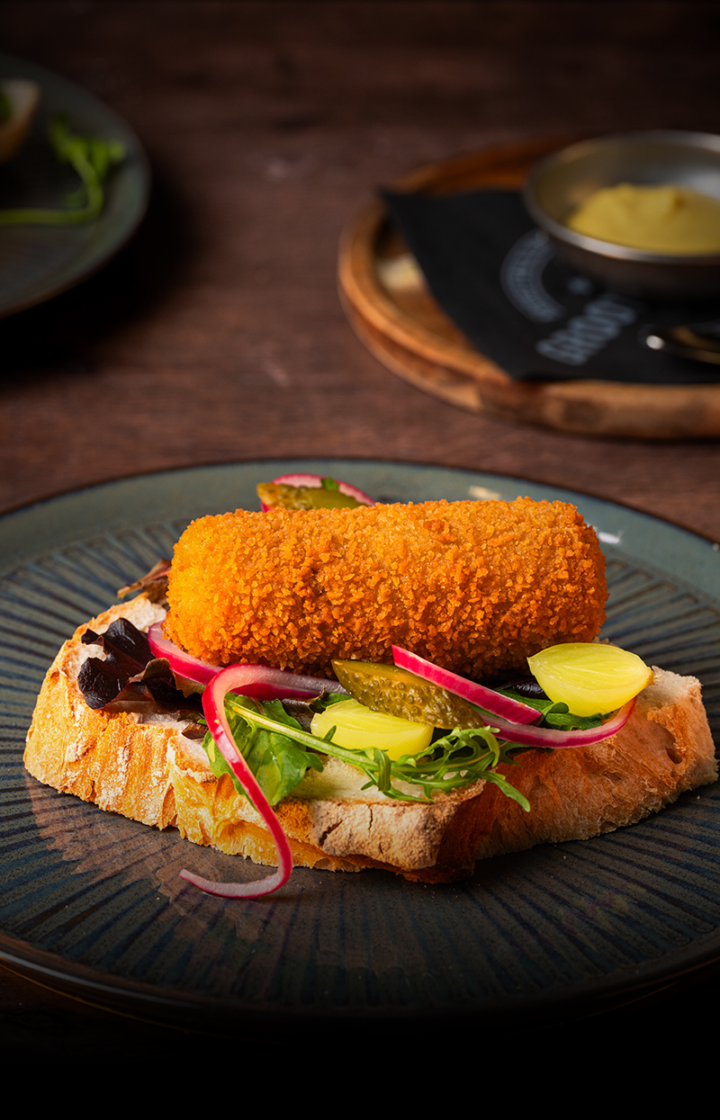 Grootmeester kroket met krokante korst op een broodje geserveerd